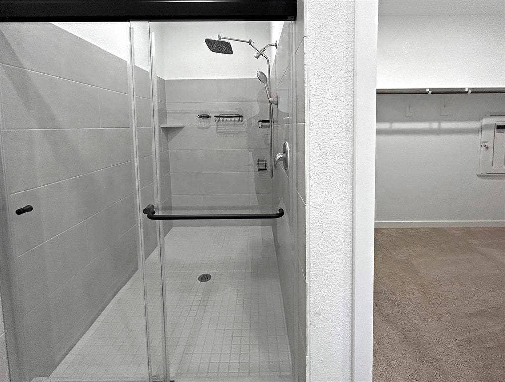 2504 Clyde Road, Celina, TX 75009 Walk-in shower featuring large-format wall tile, glass enclosure with matte black hardware, rainfall shower head, and adjustable handheld sprayer