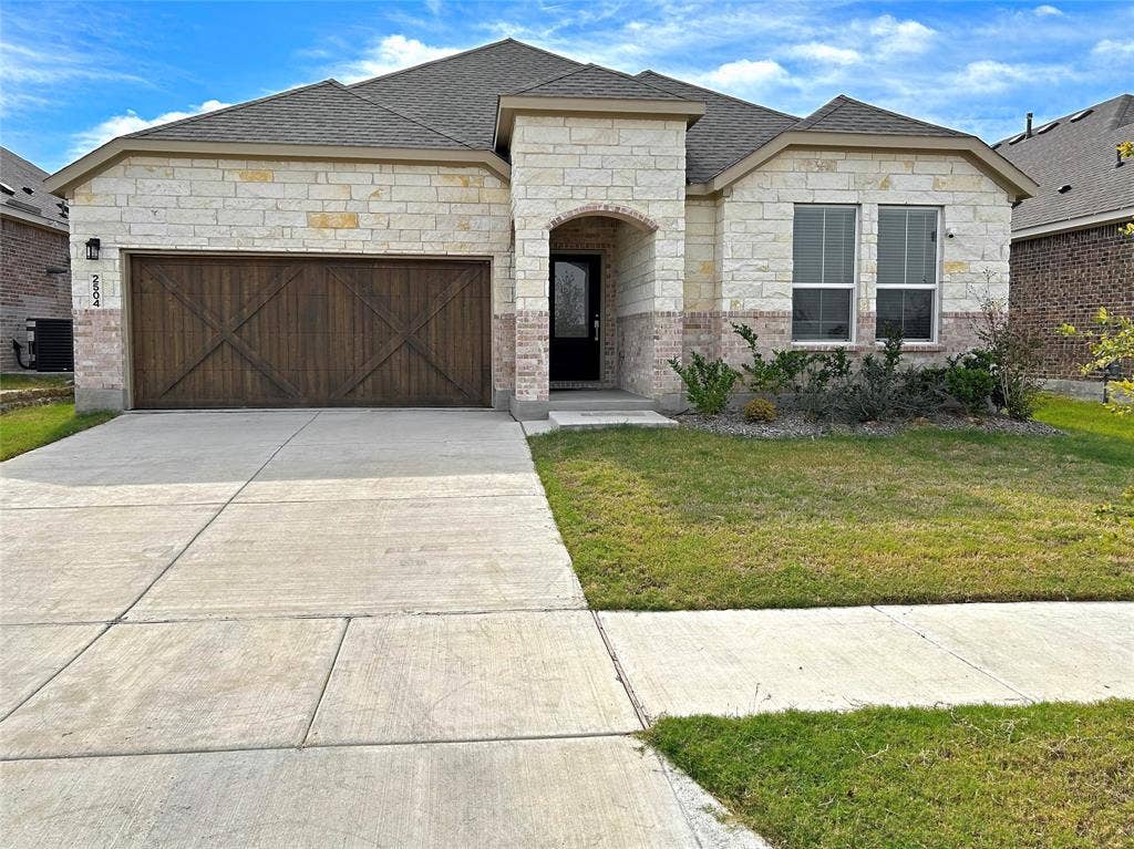 2504 Clyde Road, Celina, TX 75009 Single-story exterior featuring light-toned masonry, wood-finish garage door with X-brace detailing, multi-hipped roof, and concrete driveway