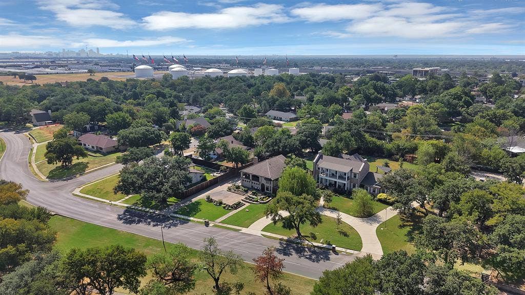 306 E Rochelle Boulevard, Irving, TX 75062 Aerial perspective of a multi-story residence featuring a circular concrete driveway, extensive tree canopy, manicured lawn, and large-scale hardscaping