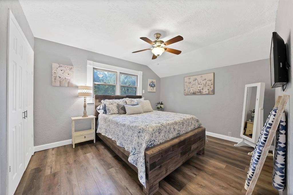 306 E Rochelle Boulevard, Irving, TX 75062 Bedroom featuring wood-finish flooring, vaulted ceiling, double-door closet, and a multi-blade ceiling fan with integrated lighting