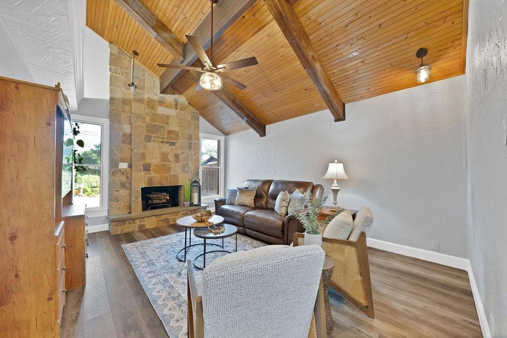 306 E Rochelle Boulevard, Irving, TX 75062 Vaulted ceiling with natural wood planking and exposed beams, full-height stone masonry fireplace, and wood-finish flooring