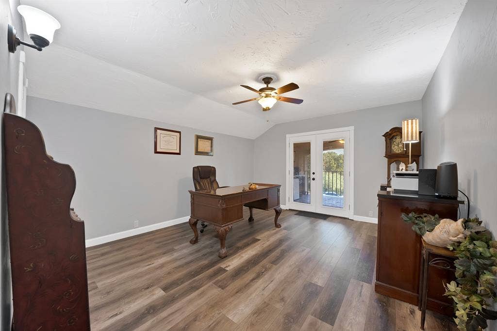 306 E Rochelle Boulevard, Irving, TX 75062 Vaulted ceilings, wood-finish flooring, central ceiling fan with integrated lighting, wall-mounted sconce, and glass-paneled double doors