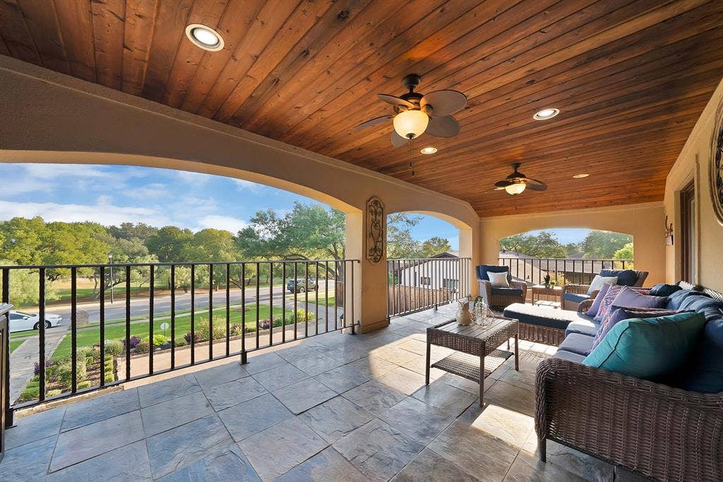 306 E Rochelle Boulevard, Irving, TX 75062 Covered balcony featuring a wood-plank ceiling, recessed lighting, ceiling fans, stone-finish tile flooring, and wrought iron railings