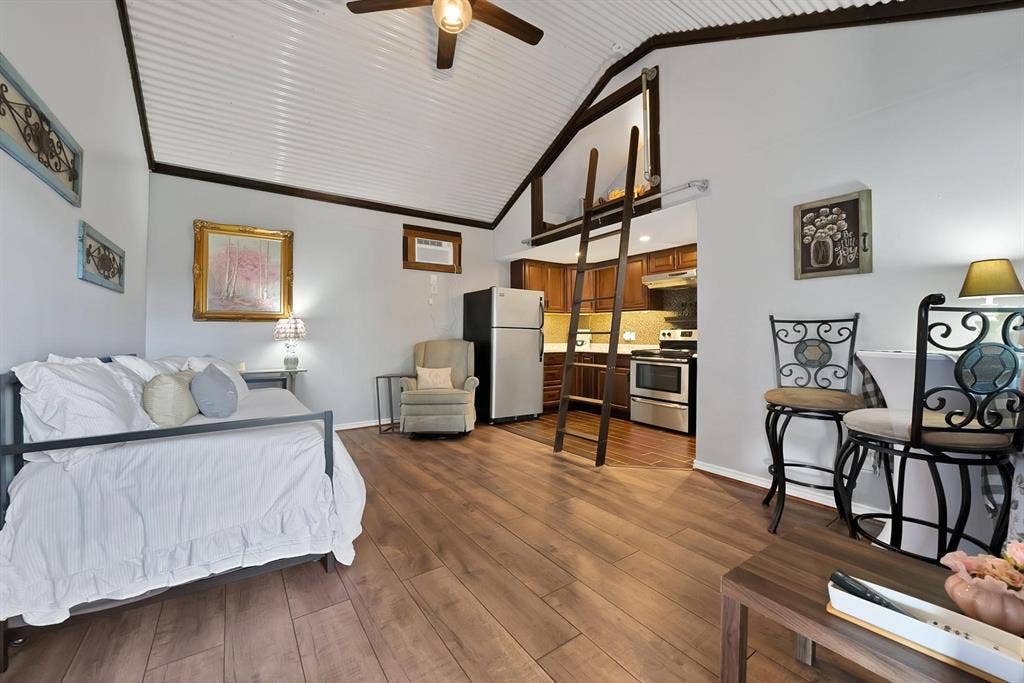 306 E Rochelle Boulevard, Irving, TX 75062 Vaulted ceiling with corrugated metal finish, wood-finish flooring, loft area with access ladder, and kitchen with dark-finish cabinetry