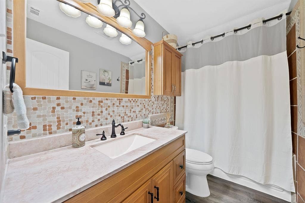306 E Rochelle Boulevard, Irving, TX 75062 Bathroom vanity featuring a wood-tone cabinet, integrated sink, and light-toned solid surface countertop