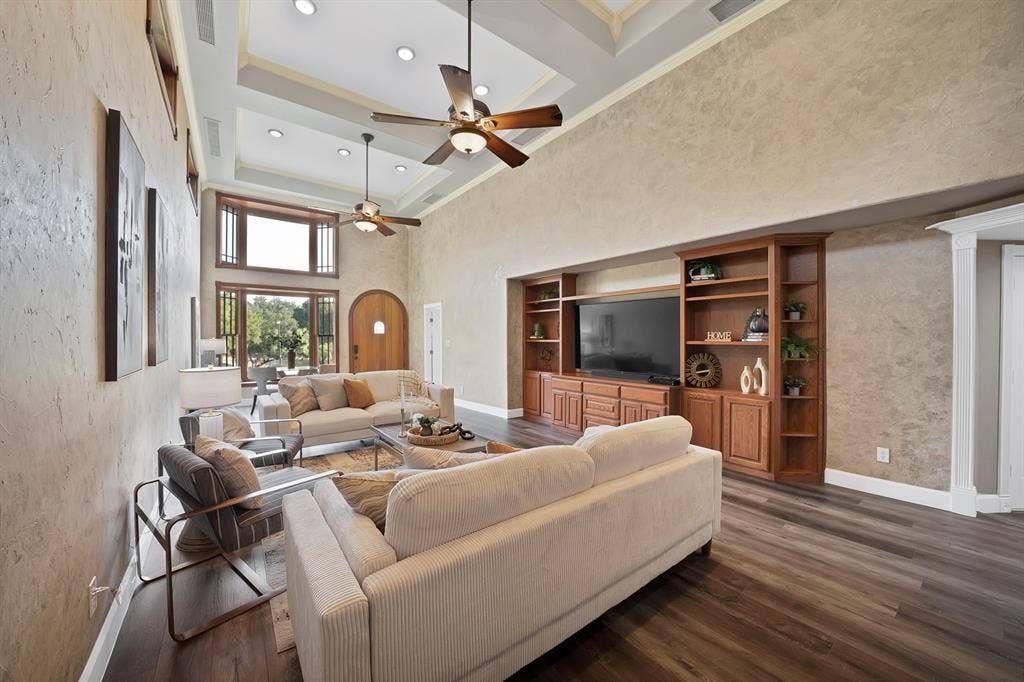 306 E Rochelle Boulevard, Irving, TX 75062 Living area featuring double-height ceilings with a coffered design, built-in wooden cabinetry with integrated shelving, wood-finish flooring, and multi-pane windows