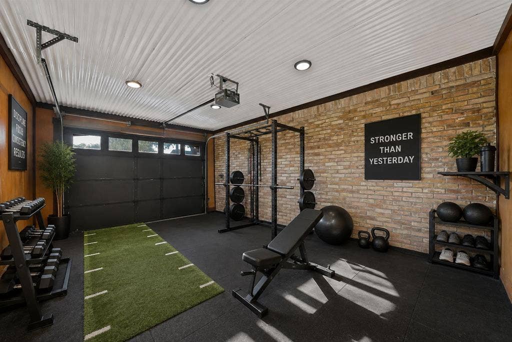 306 E Rochelle Boulevard, Irving, TX 75062 Multi-use space featuring corrugated metal ceiling panels, exposed brick wall, rubberized flooring, recessed lighting, and a multi-panel garage door