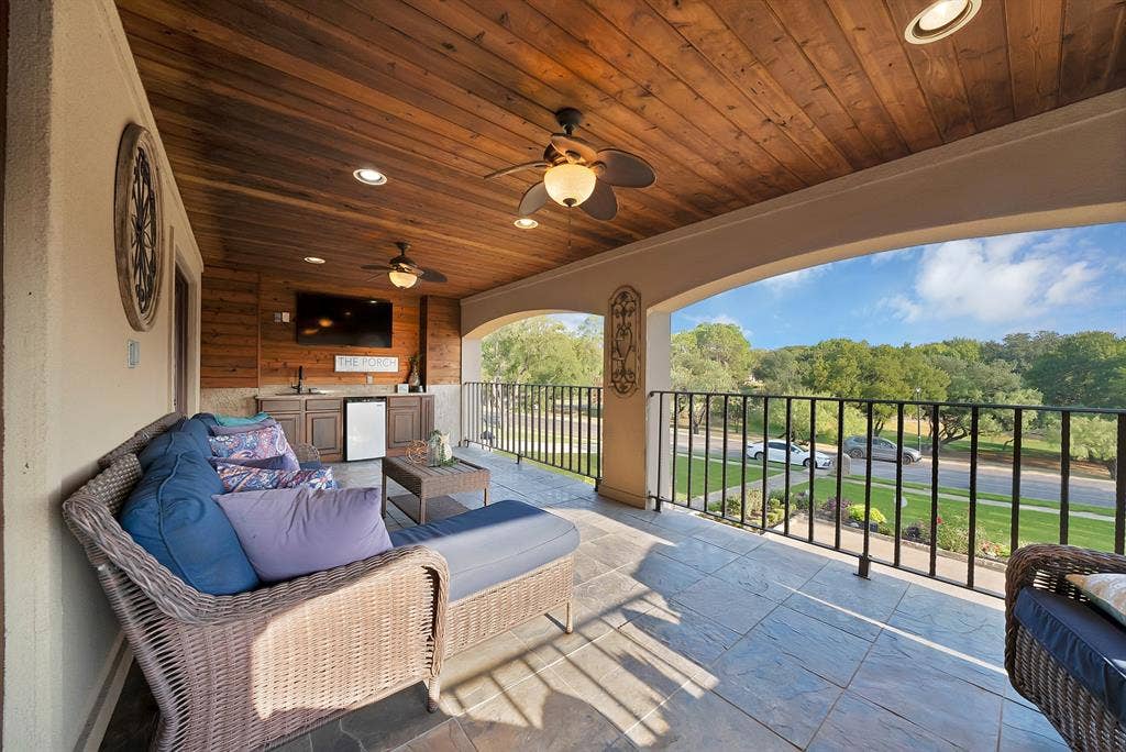 306 E Rochelle Boulevard, Irving, TX 75062 Covered balcony featuring a wood-plank ceiling, built-in wet bar, recessed lighting, ceiling fans, and black metal railings