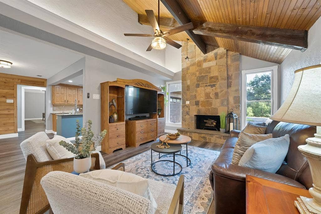 306 E Rochelle Boulevard, Irving, TX 75062 Vaulted ceiling featuring wood-plank paneling and exposed structural beams, floor-to-ceiling stone fireplace, and wood-finish flooring