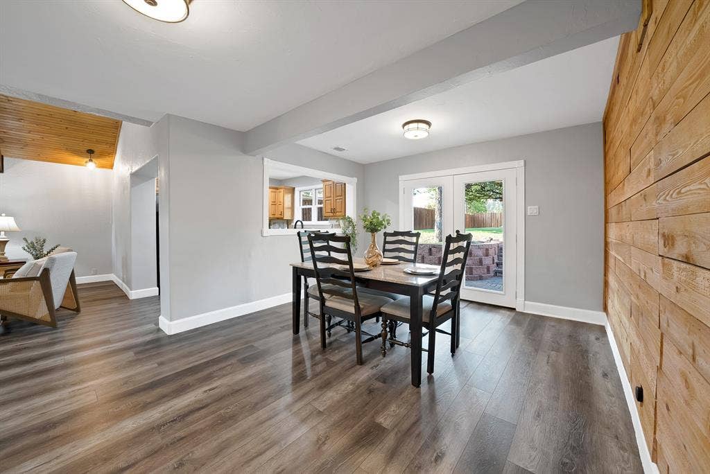 306 E Rochelle Boulevard, Irving, TX 75062 Interior space featuring wood-finish flooring, a horizontal wood-plank accent wall, dual glass-paneled exterior doors, and a service window opening