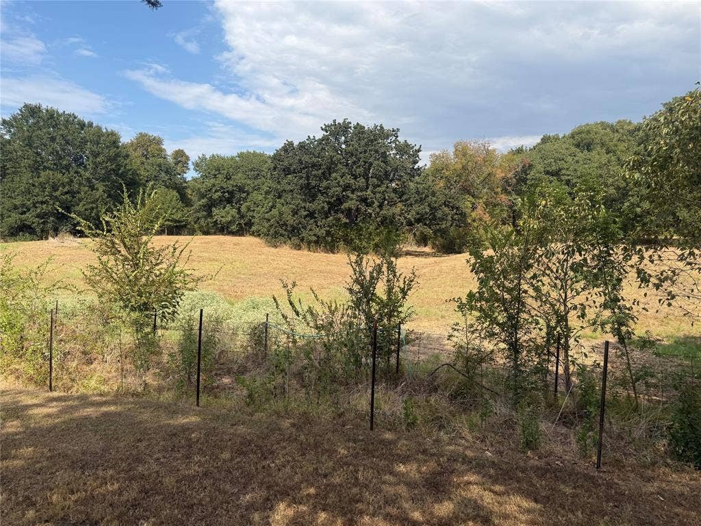Expansive acreage featuring mature trees, natural vegetation, and wire fencing