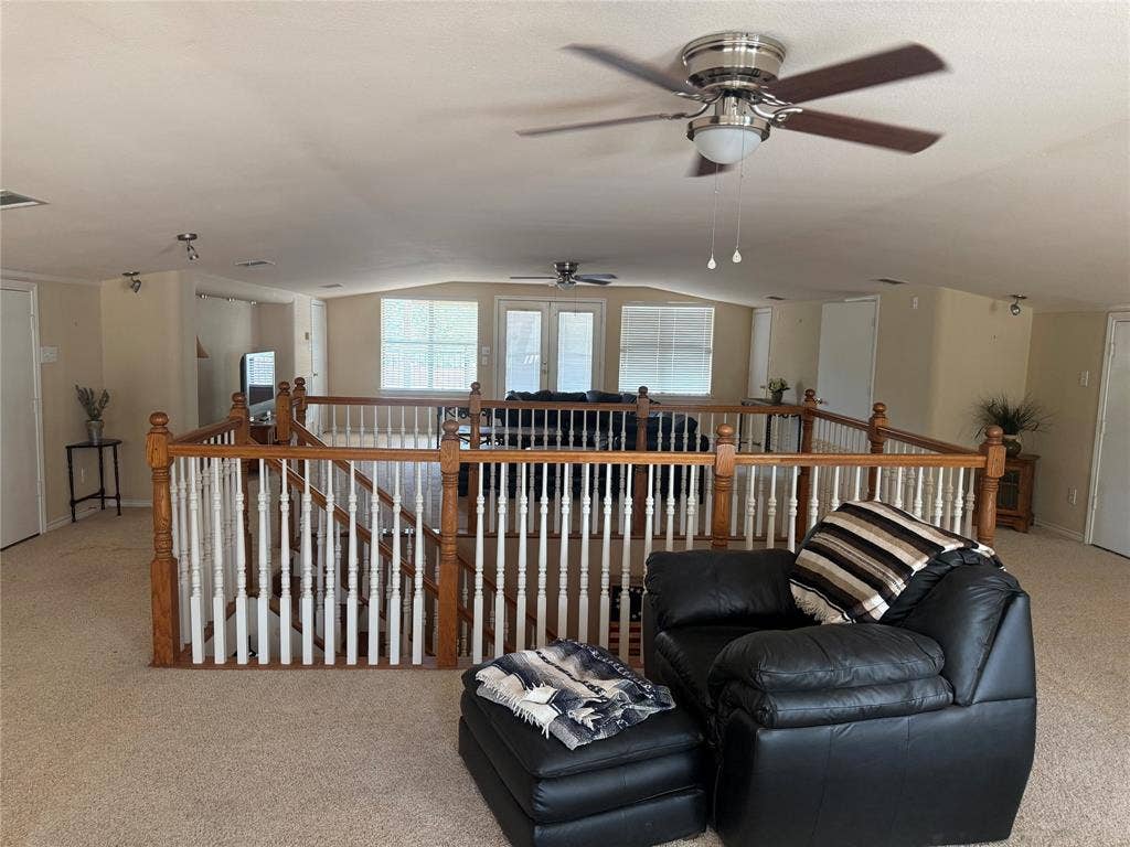 Spacious interior featuring a wooden balustrade with white spindles, multiple ceiling fans, recessed lighting, and large windows