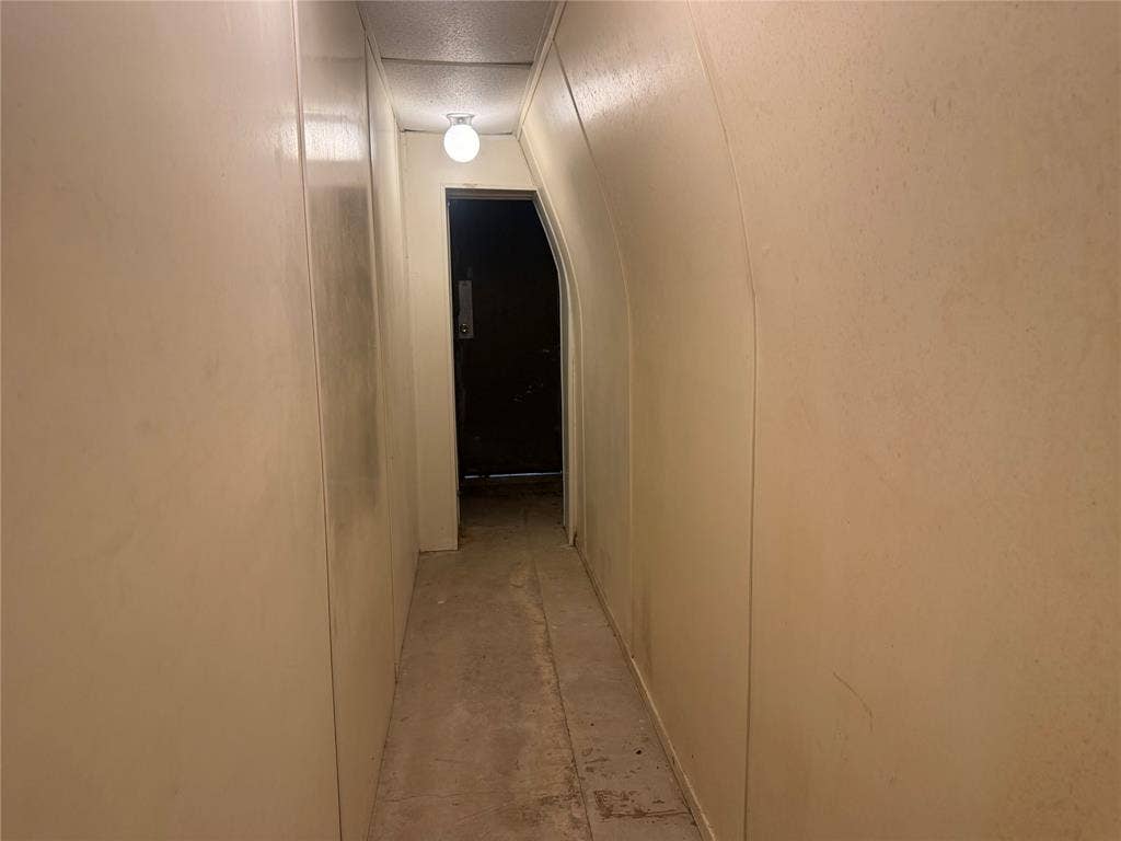 Arched hallway featuring smooth-finish walls and a globe-style flush-mount ceiling light fixture