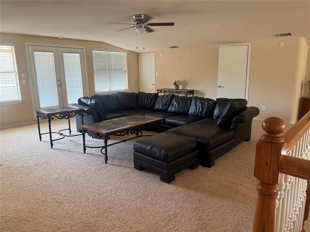 Neutral-toned room featuring high-pile wall-to-wall carpeting, ceiling fan with light fixture, glass-paneled double doors, second living space or bedroom 3