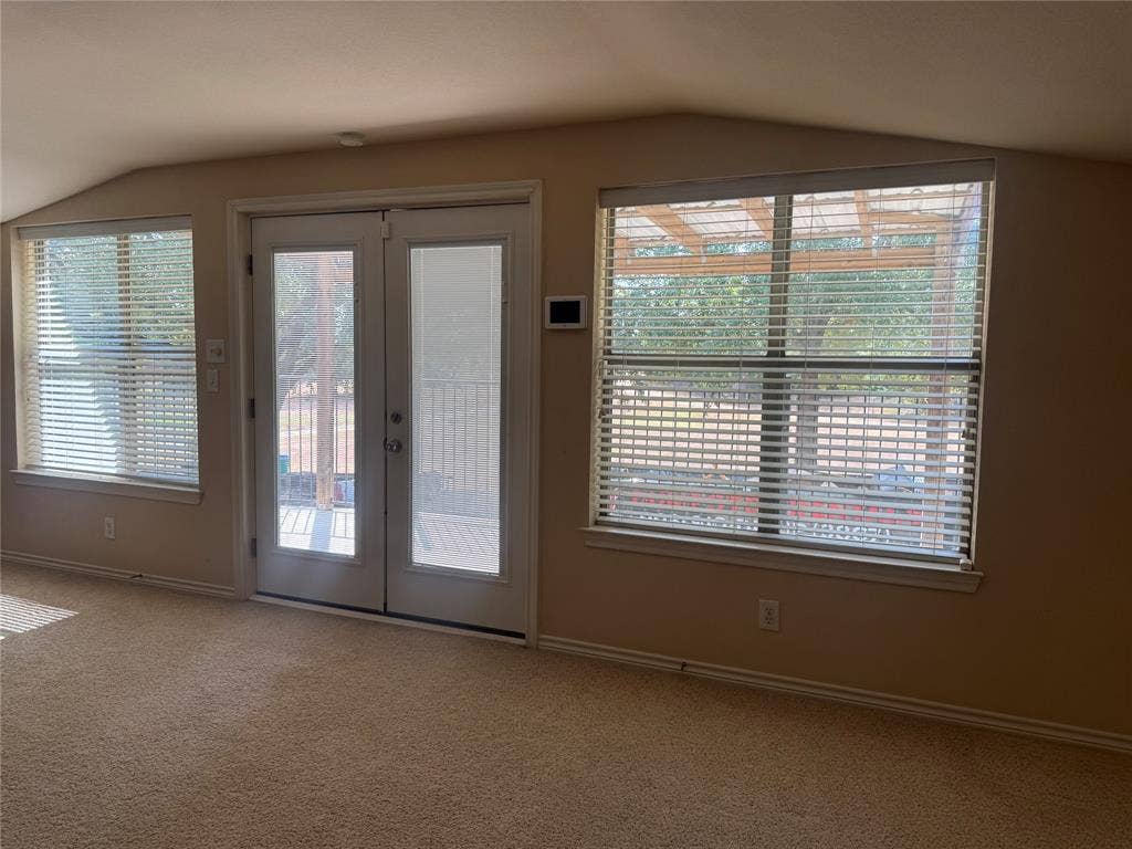 Glass-paned double doors with integrated sidelights, dual large windows, and neutral carpeting to balcony