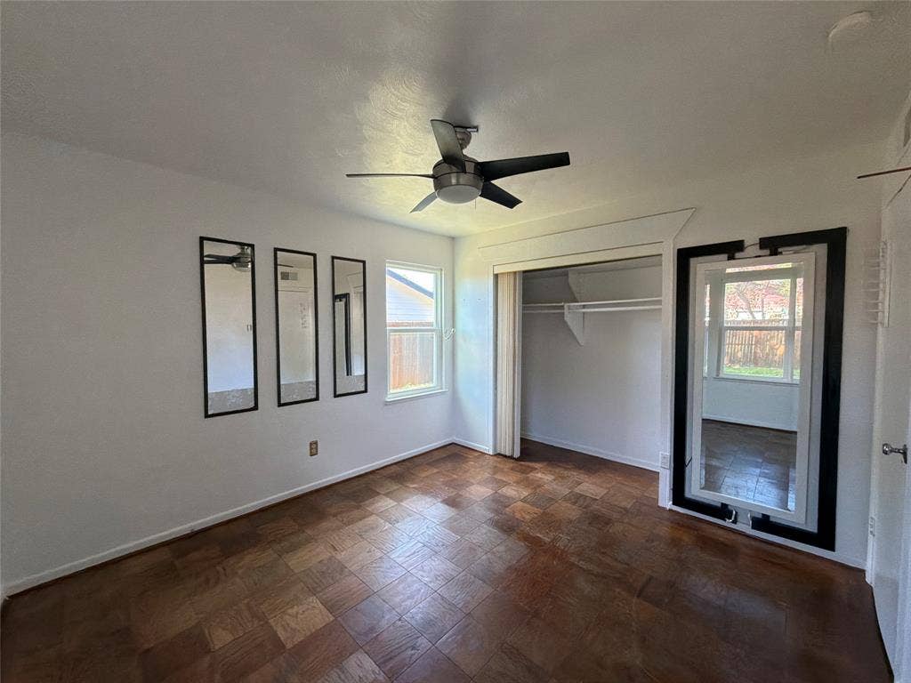 1819 Finley Road, Irving, TX 75062 Parquet wood-finish flooring, ceiling fan with integrated lighting, built-in closet with sliding door, and wall-mounted rectangular mirrors