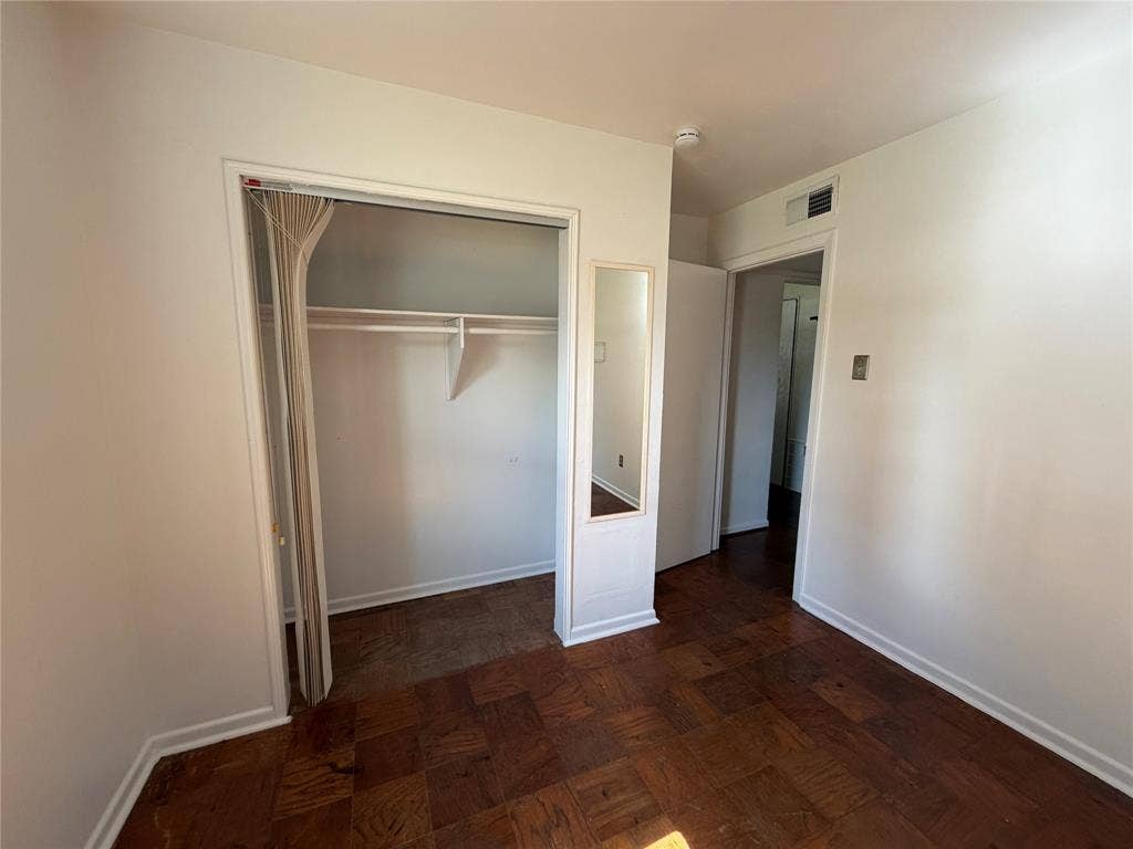 1819 Finley Road, Irving, TX 75062 Parquet wood-finish flooring throughout, closet featuring a built-in shelf and hanging rod, and a recessed wall-mounted mirror