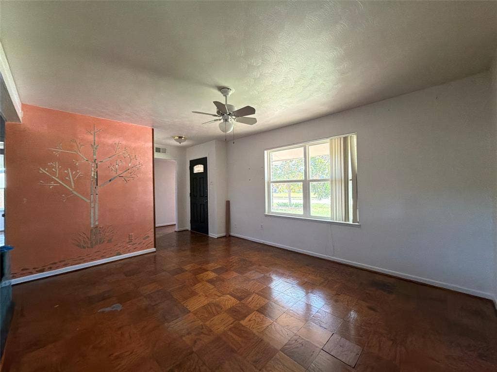 1819 Finley Road, Irving, TX 75062 Parquet wood-finish flooring, accent wall with decorative mural, ceiling fan with integrated light fixture, and multipane window