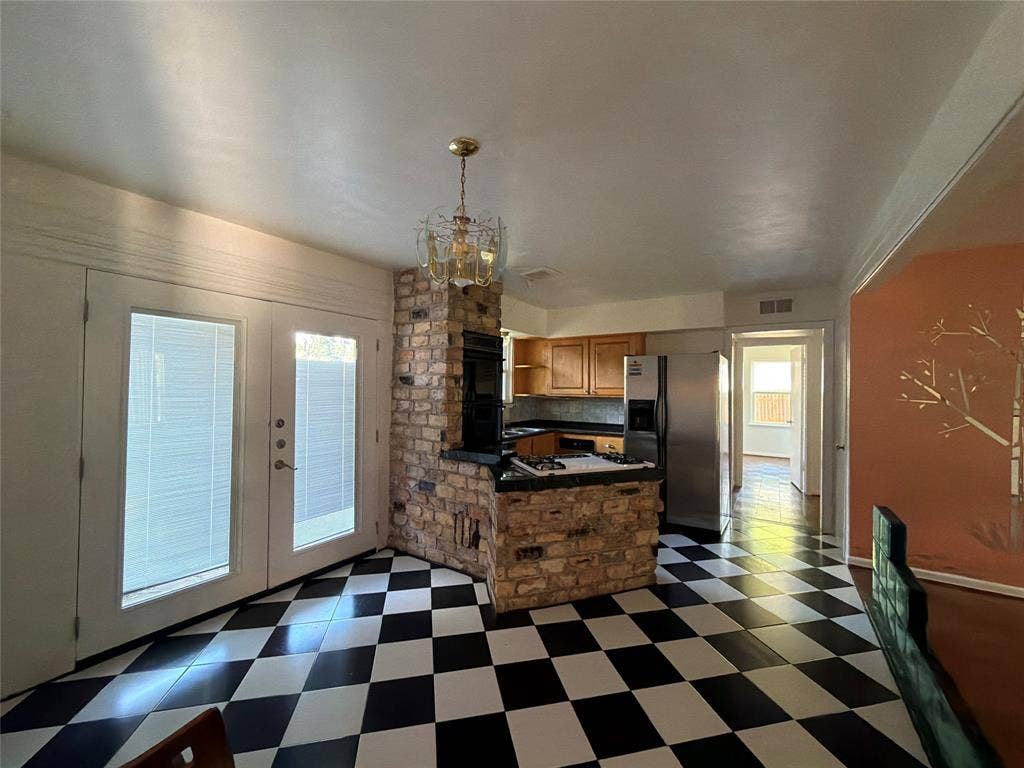1819 Finley Road, Irving, TX 75062 Checkerboard tile flooring, brick-surround cooking island, dual glass-paneled exterior doors, and a multi-arm metal chandelier