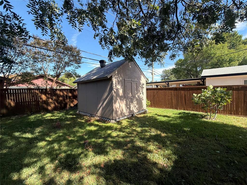 1819 Finley Road, Irving, TX 75062 Detached storage structure featuring vertical siding, a pitched roof, and double-door entry, situated within a fenced backyard