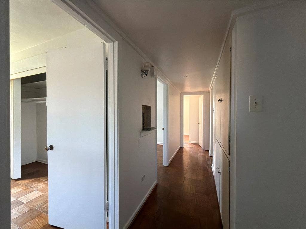 1819 Finley Road, Irving, TX 75062 Hallway featuring parquet wood-finish flooring, built-in floor-to-ceiling storage cabinetry, and a recessed wall niche