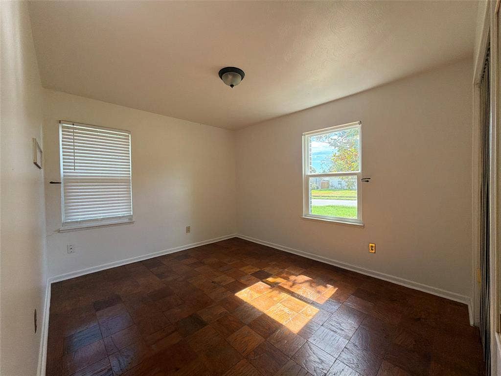 1819 Finley Road, Irving, TX 75062 Room featuring parquet wood-finish flooring, two windows with blinds, and a flush-mount ceiling light fixture