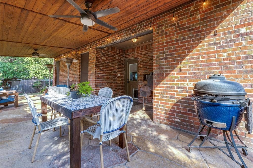 Cedar covered patio featuring stamped concrete floor, plank ceiling, brick exterior walls, equipped with ceiling fan