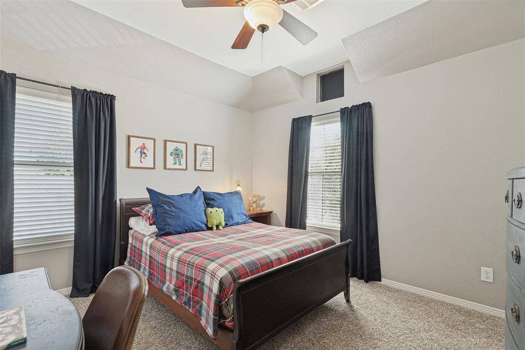 Secondary bedroom with a centrally mounted ceiling fan, neutral wall tones, carpeted flooring, and windows featuring horizontal blinds