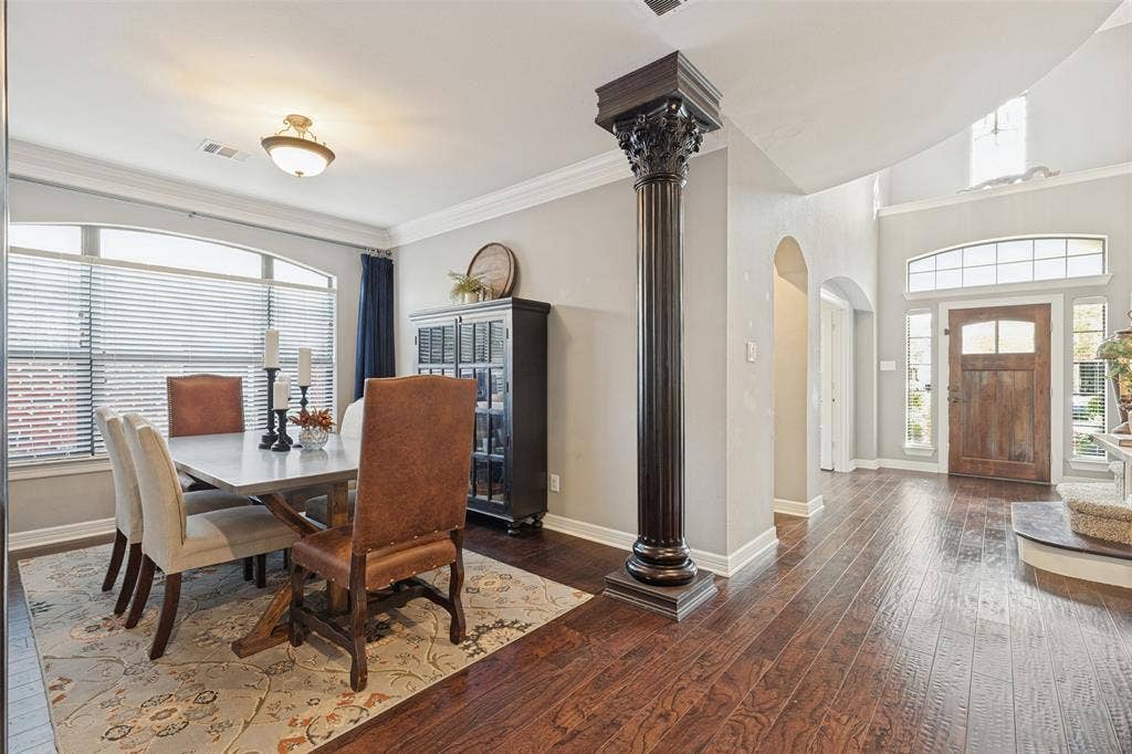 Dark wood-finish flooring, decorative Corinthian-style column, arched doorways, arched window transoms, and wood-paneled front door