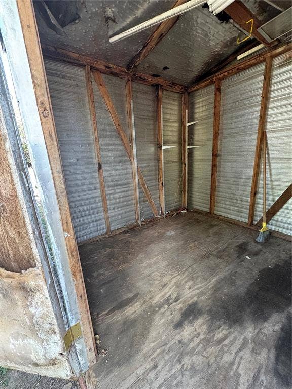 Outbuilding featuring exposed wood framing, corrugated metal wall paneling, and a plywood floor