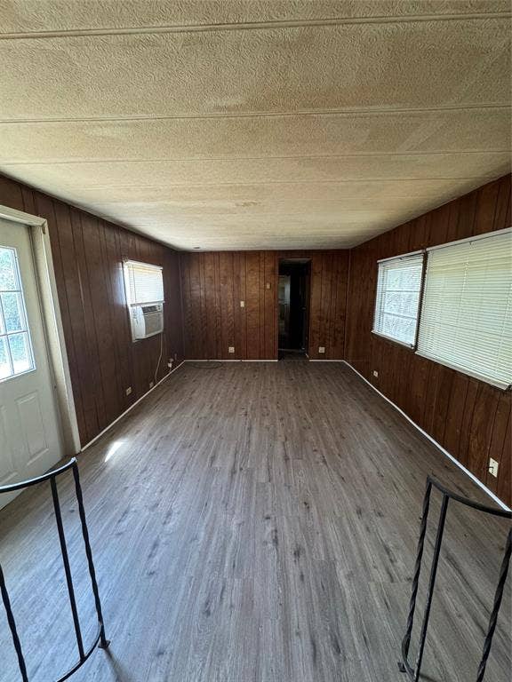 Interior space featuring wood-finish paneling, wood-finish flooring, multi-pane glass entry door, and large windows with horizontal blinds
