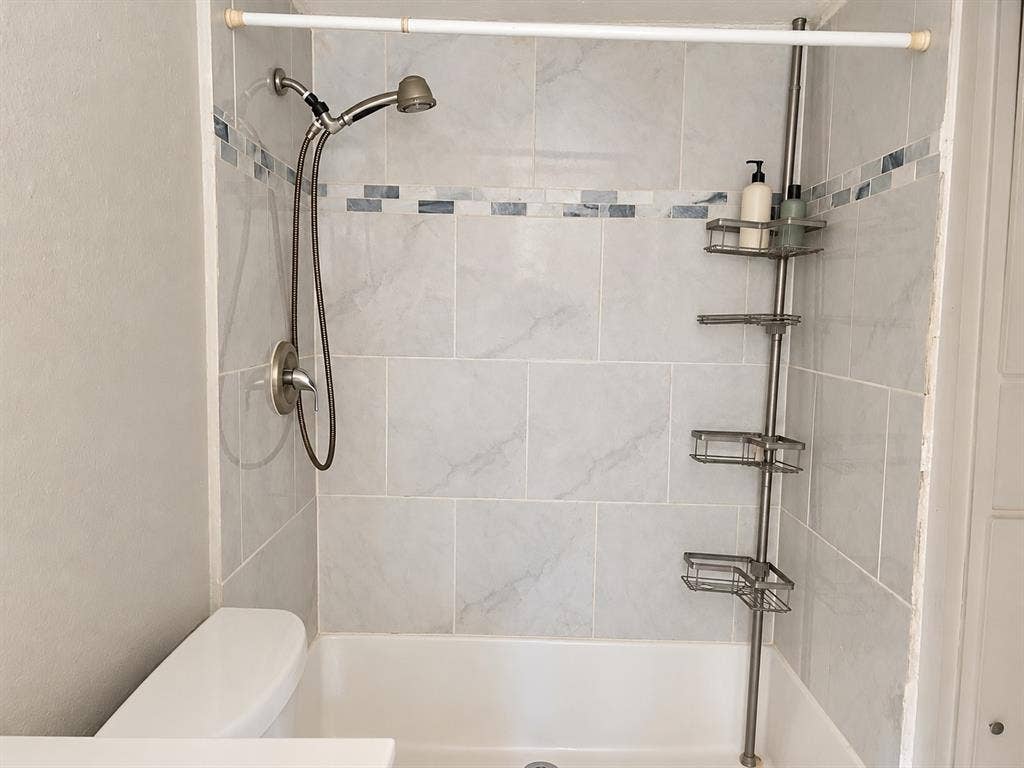 Shower featuring full-height tile surround, horizontal mosaic decorative inlay, and brushed-nickel handheld shower fixture