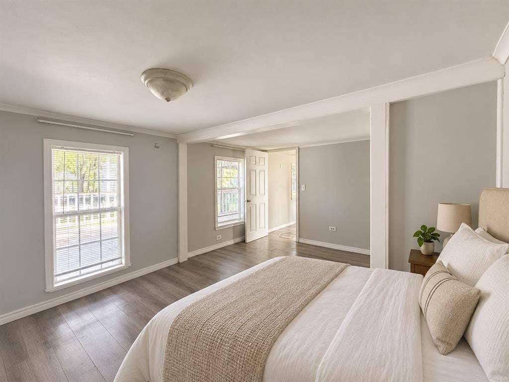 Neutral-toned interior featuring wood-finish flooring, multi-pane windows, crown molding, and a dome ceiling light fixture