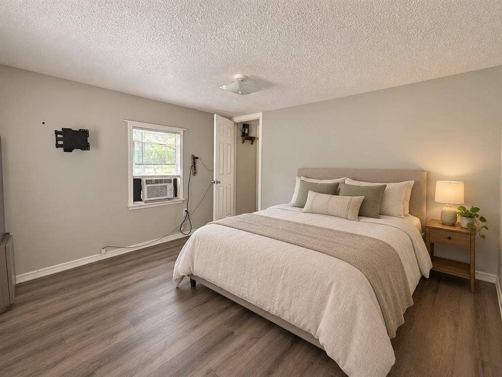 Neutral-toned bedroom featuring wood-finish flooring, a single-hung window, and a flush-mount ceiling light fixture
