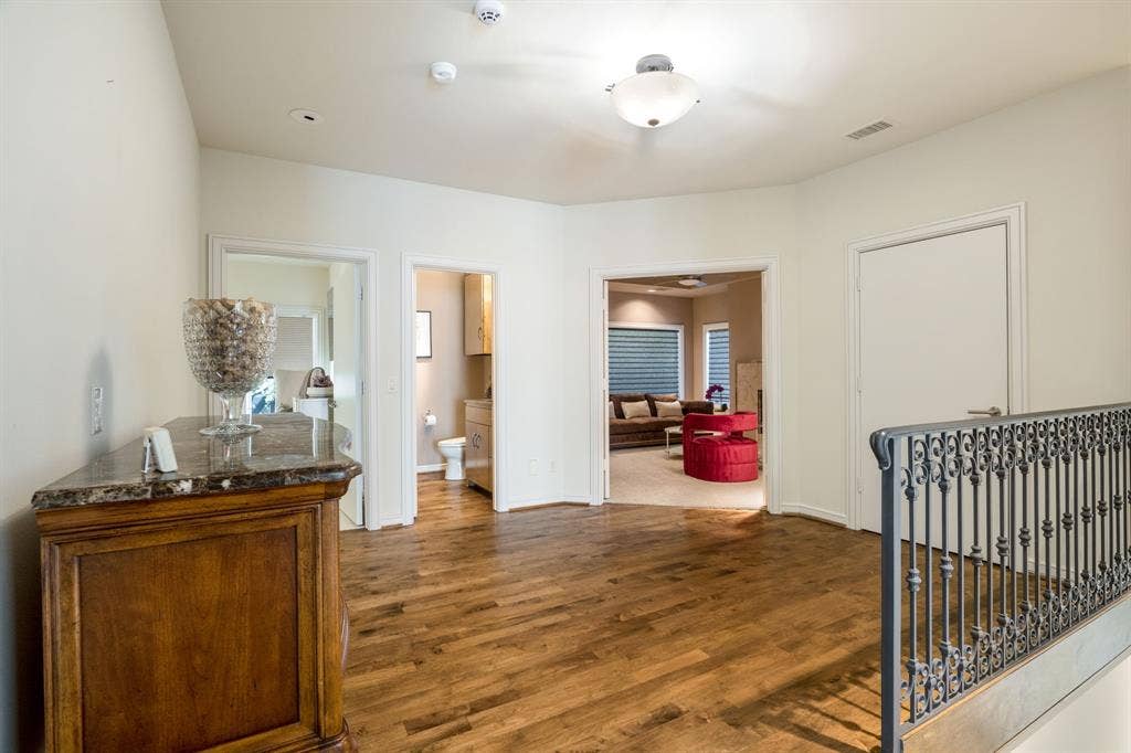 Wood-finish flooring, decorative metal stair railing, and neutral wall tones