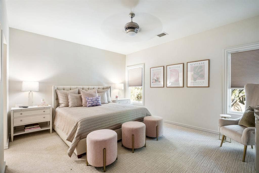 Neutral interior featuring high ceilings, neutral wall-to-wall carpeting, ceiling fan with integrated lighting, and multiple windows with pleated shades