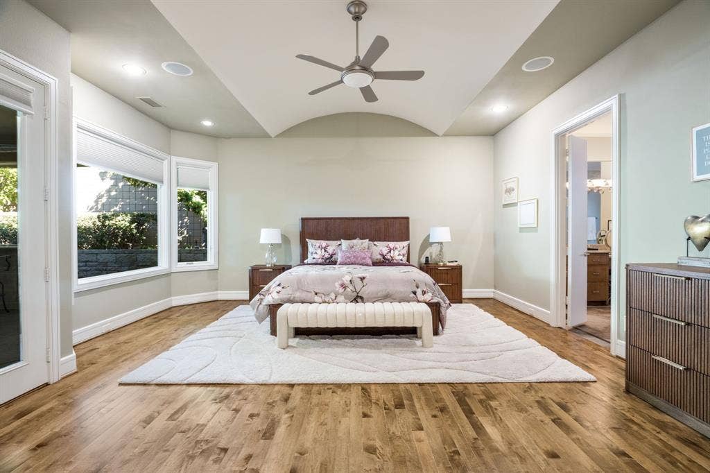 Barrel-vaulted ceiling featuring a central brushed-nickel ceiling fan, bay window configuration, recessed lighting, and wood-finish flooring