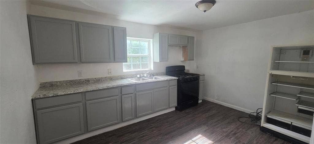 3510 Marshall Street, Greenville, TX 75401 Kitchen featuring grey cabinetry, stone-finish countertops, wood-finish flooring, dual-basin sink, and dark-finish appliances