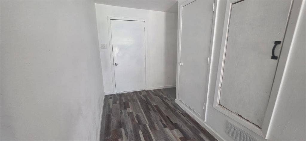 3510 Marshall Street, Greenville, TX 75401 Interior space featuring wood-finish flooring, two sets of built-in wall cabinetry with recessed panels, and a single-panel interior door