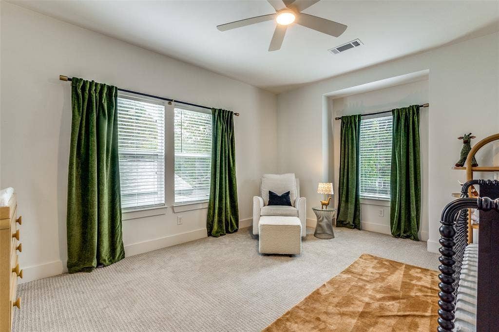 Neutral-toned wall-to-wall carpeting, multiple windows providing natural light, recessed ceiling area, and a ceiling fan with integrated lighting