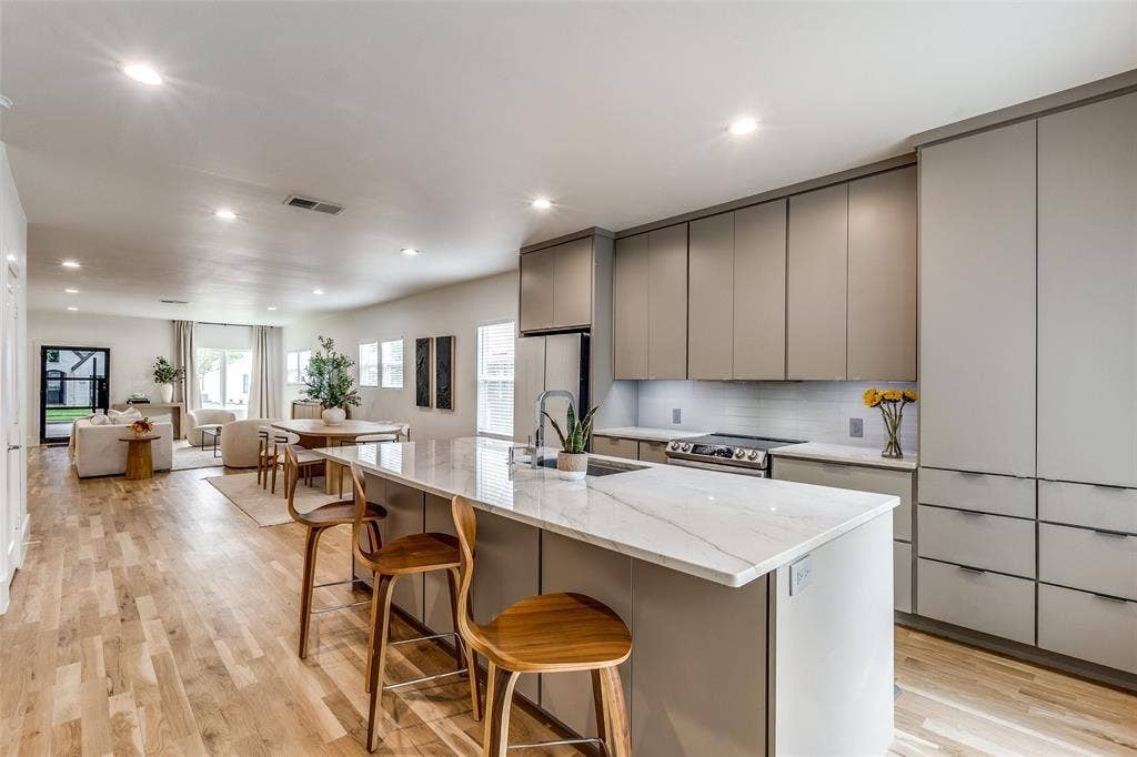 Kitchen featuring a large island with a stone countertop, flat-panel cabinetry, recessed lighting, and wood-finish flooring
