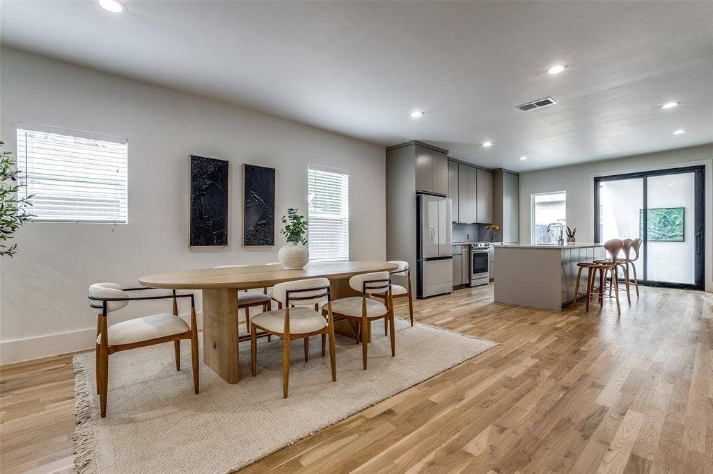 Open-concept interior featuring light wood-finish flooring, recessed lighting, neutral wall finishes, flat-panel cabinetry, and a central island with a quartz countertop