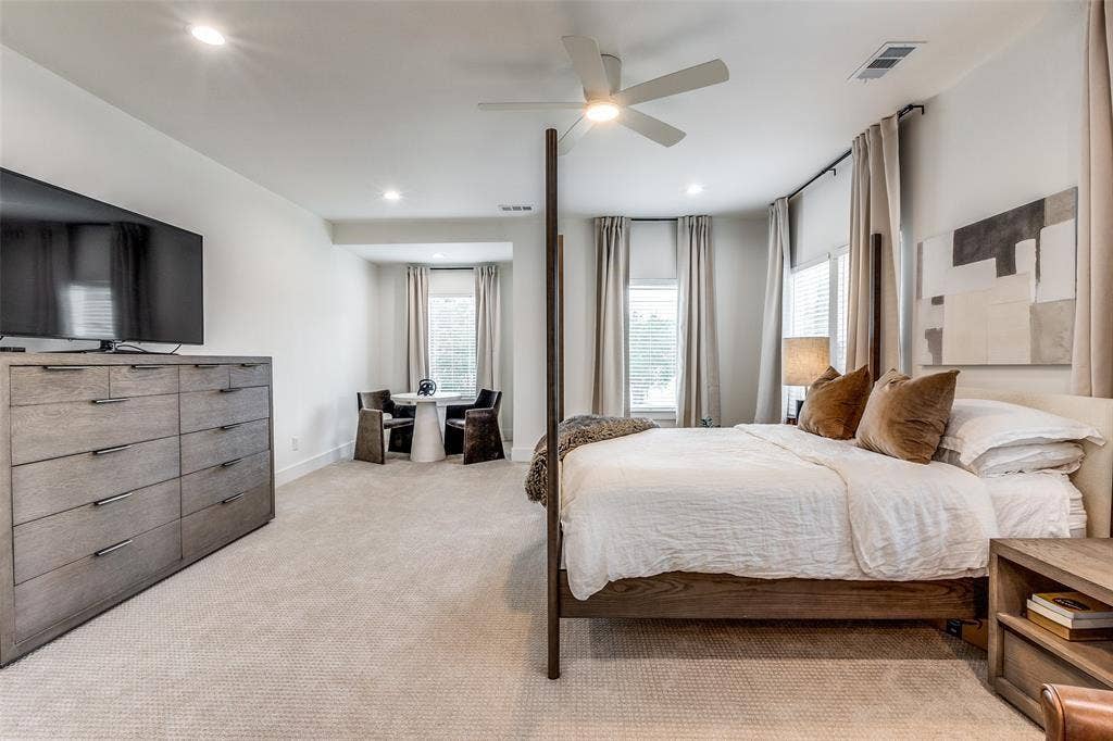 Neutral-toned carpeted flooring, recessed lighting, ceiling fan, and multiple windows with full-height window treatments