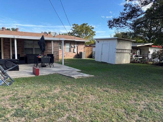 Backyard featuring a concrete patio, exterior brick siding, and a detached storage structure
