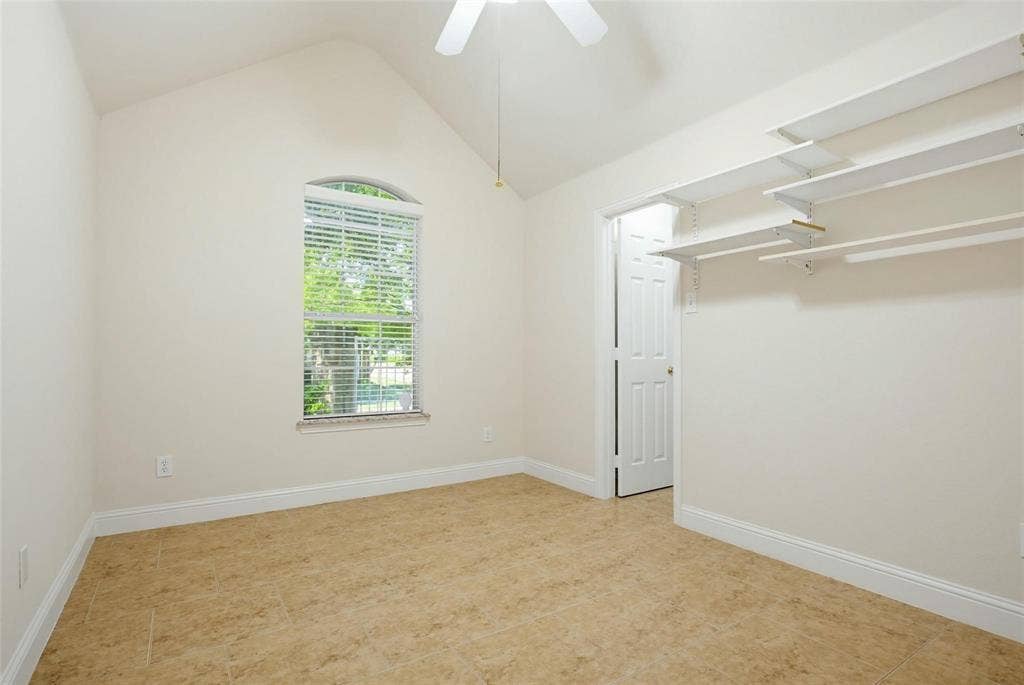 4402 Horizon Drive, Garland, TX 75043 Vaulted ceiling, arched window, tile flooring, and wall-mounted shelving units