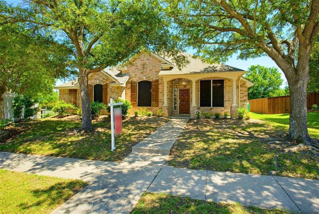 4402 Horizon Drive, Garland, TX 75043 Single-story brick exterior featuring a covered front porch, arched window detailing, wood-finish shutters, and mature trees