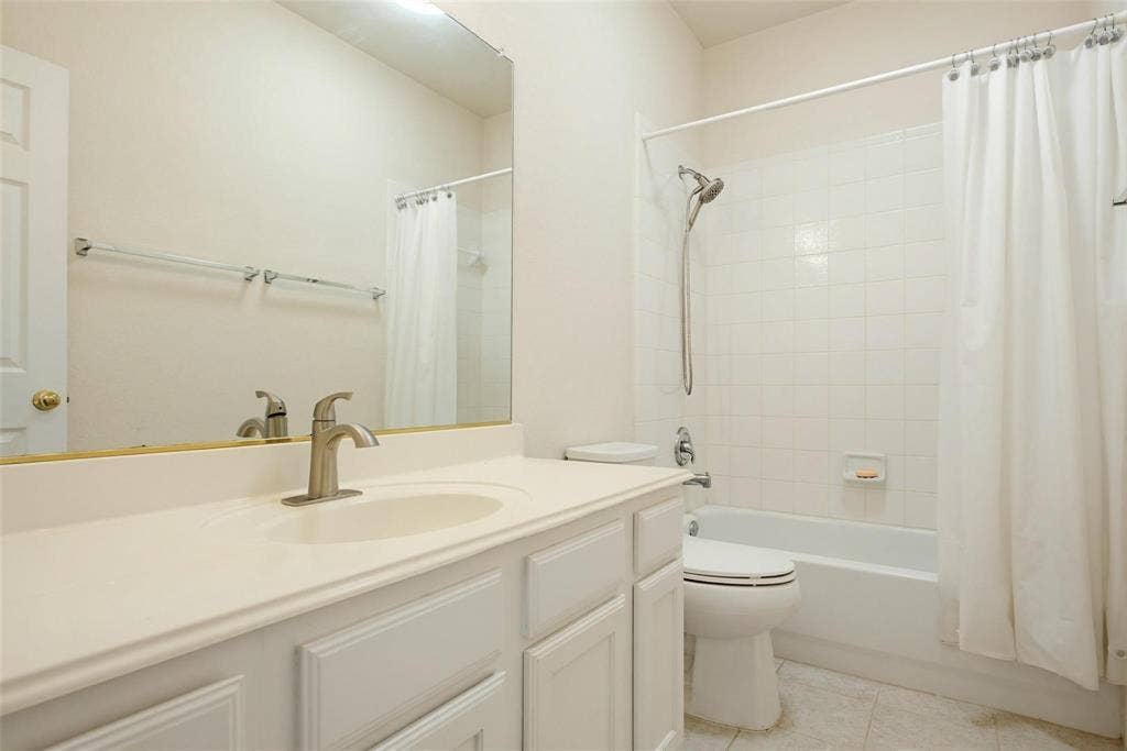 4402 Horizon Drive, Garland, TX 75043 Bathroom featuring a vanity with an integrated countertop, large wall-mounted mirror, brushed nickel faucet, and a shower-tub combination with white tile surround