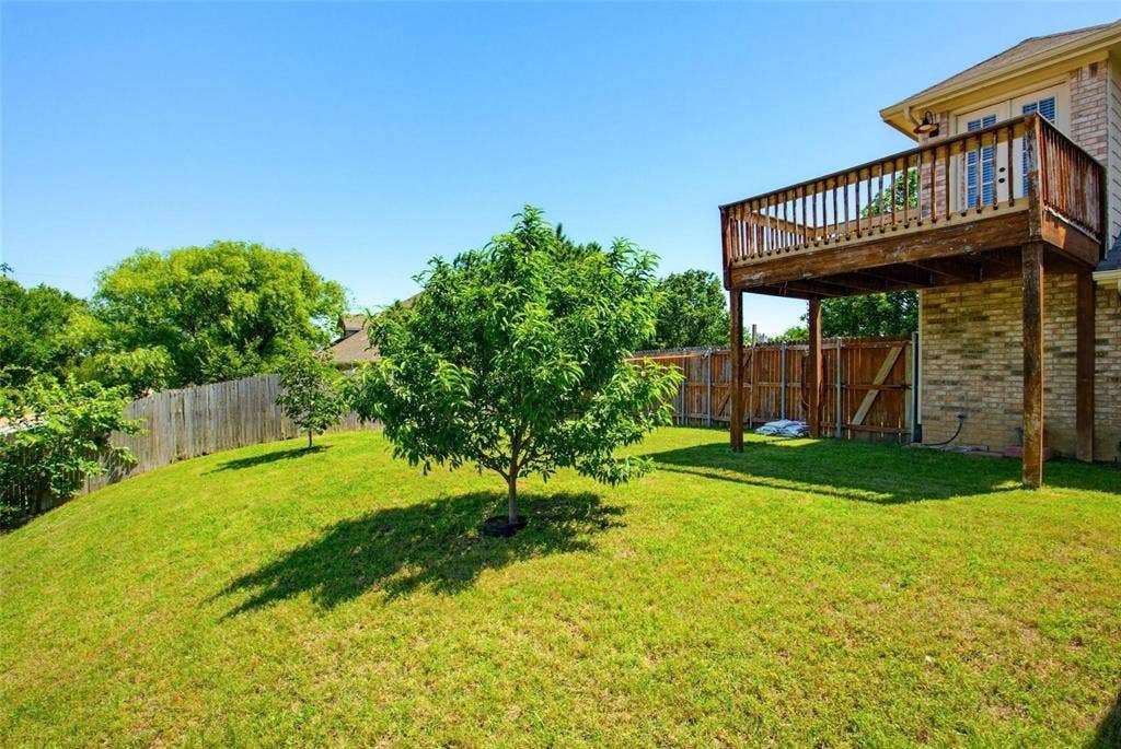 4402 Horizon Drive, Garland, TX 75043 Backyard featuring a grass lawn, wood-framed elevated deck, brick exterior siding, and perimeter wood fencing