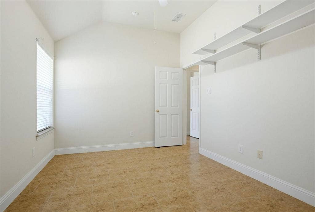 4402 Horizon Drive, Garland, TX 75043 Room featuring a vaulted ceiling, neutral-toned tile flooring, and two tiers of wall-mounted shelving