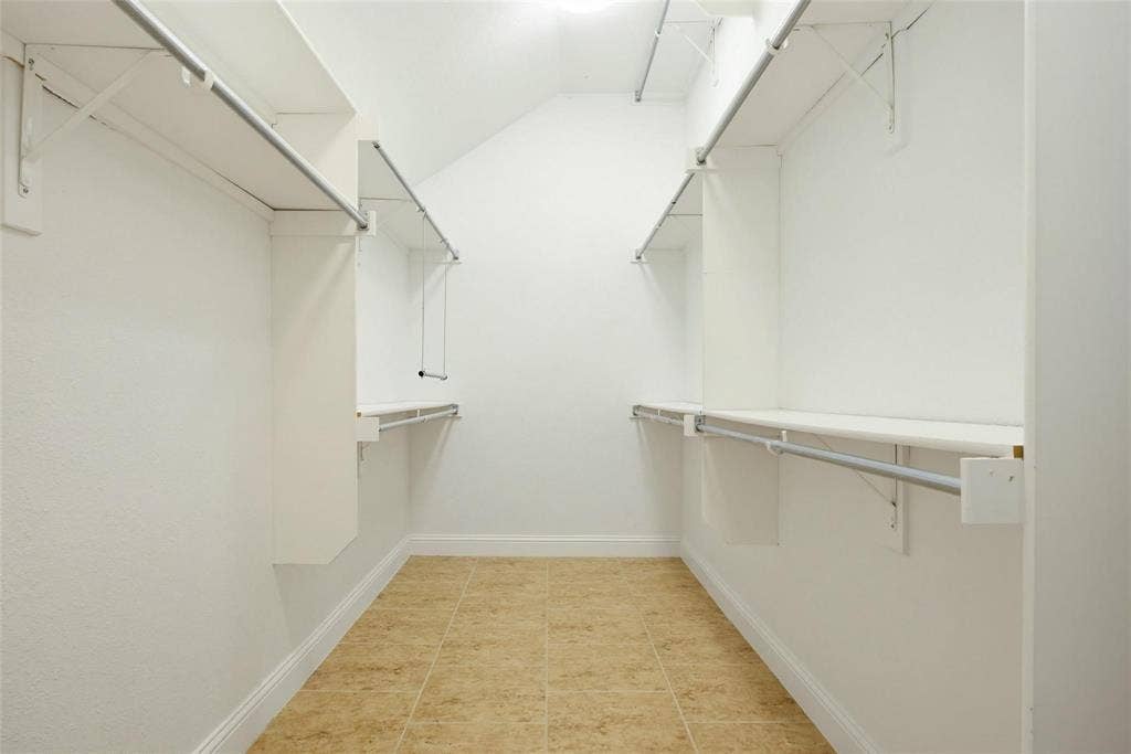 4402 Horizon Drive, Garland, TX 75043 Walk-in closet featuring dual-sided built-in shelving, adjustable metal clothing rods, and tile flooring